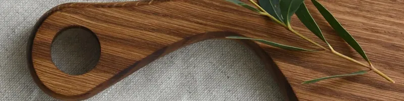 Planche en bois et branche d'olivier sur un tissu de lin